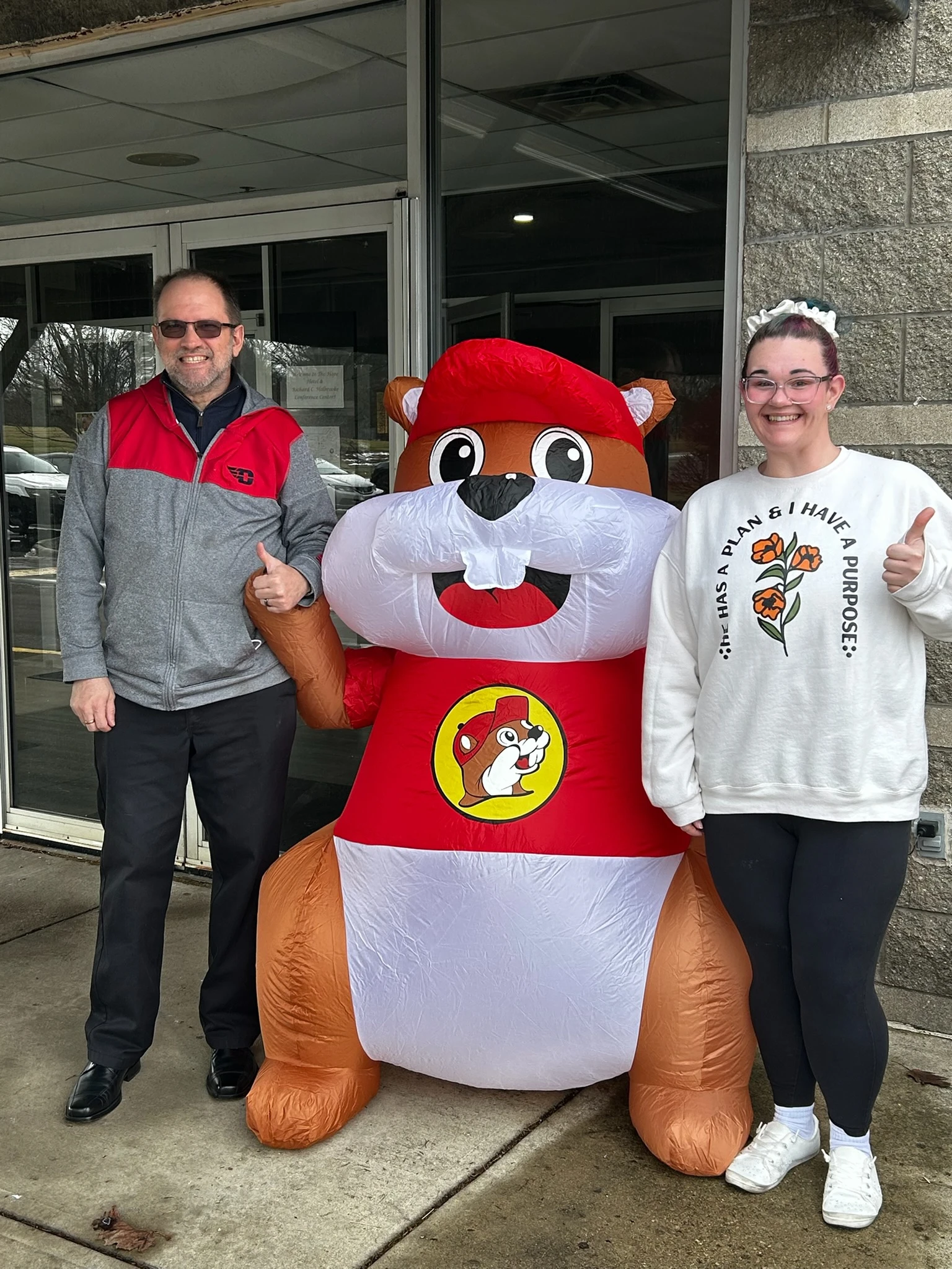 Two people smiling for a photo with a Buc-ee's inflatable